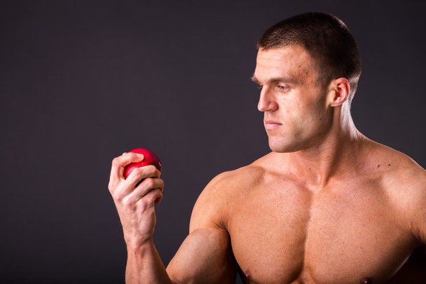 Muscular man holding ripe apple - Foto, afbeelding