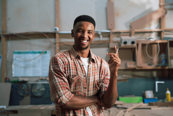 Amistoso hombre de negocios afroamericano con camisa a cuadros en la fábrica de carpintería Foto de alta calidad - Foto, Imagen