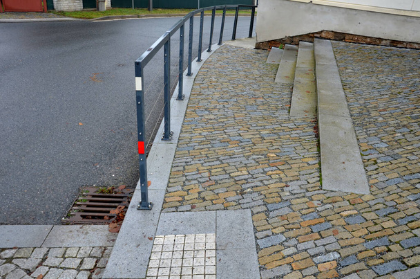 metal frames of railings are visually lightened by elegant stainless steel cables instead of horizontal bars. a intersection, they separate sidewalk school from road, students, accident, stone paving - Photo, Image