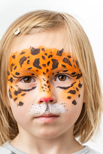 Cute little caucasian girl with tiger face painting on the white background. Close up portrait of little kid with face-painting. Year of a tiger. Happy smiling girl - Photo, Image