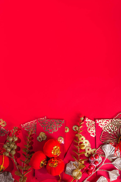 Chiński Nowy Rok złoty czerwony tło. Księżycowy Nowy Rok kartka okolicznościowa płaskowyż z tradycyjną dekoracją festiwalową - ginkgo biloba oddziały wystrój, gałązki, jagody, koperty prezent, monety, chińskie latarnie - Zdjęcie, obraz
