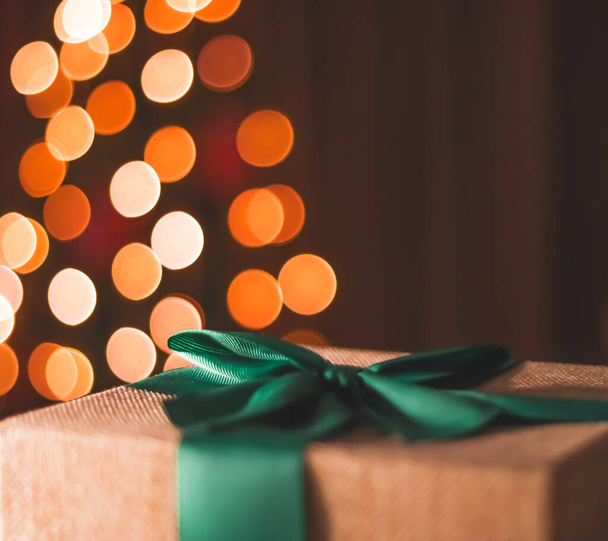 Wakacyjny nastrój i świąteczna atmosfera, zapakowany prezent i choinka światła na tle, zbliżenie - Zdjęcie, obraz