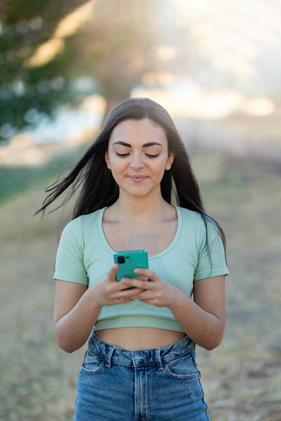 Gyönyörű barna lány vidéken használ okos telefon  - Fotó, kép