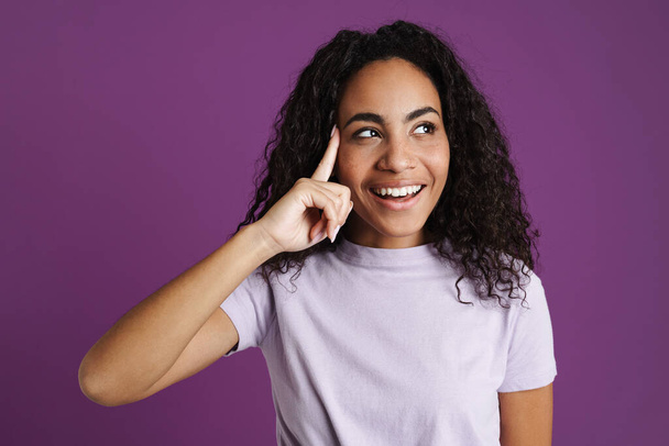 Young black woman smiling and pointing finger at her temple isolated over purple background - Foto, Imagem