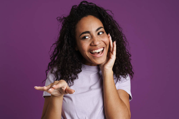 Young black woman wearing t-shirt laughing and gesturing isolated over purple background - Foto, Bild