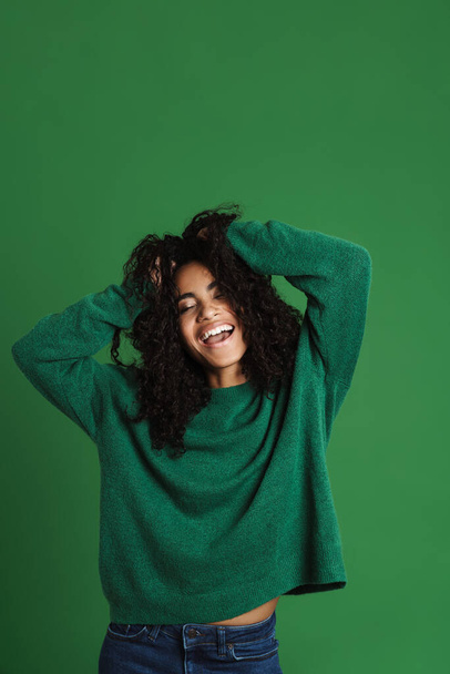 Young black woman laughing while holding her head isolated over green background - Φωτογραφία, εικόνα