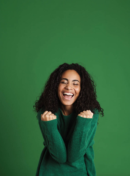 Young black woman laughing while making winner gesture isolated over green background - Foto, Imagem