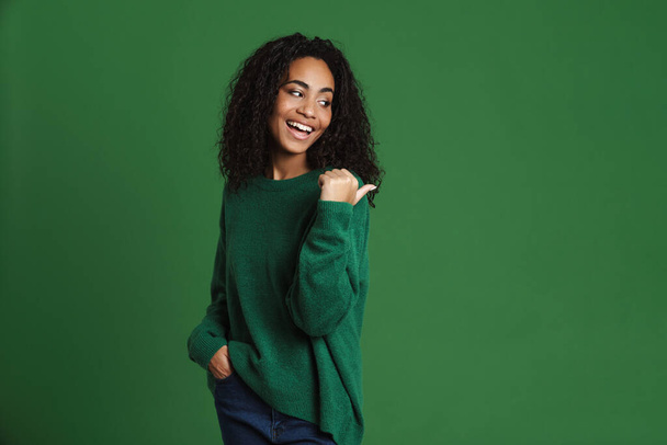 Young black woman laughing while pointing finger aside isolated over green background - Photo, image
