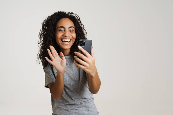 Nuori musta nainen käyttää matkapuhelinta ja tehdä ele eristetty valkoisella taustalla - Valokuva, kuva