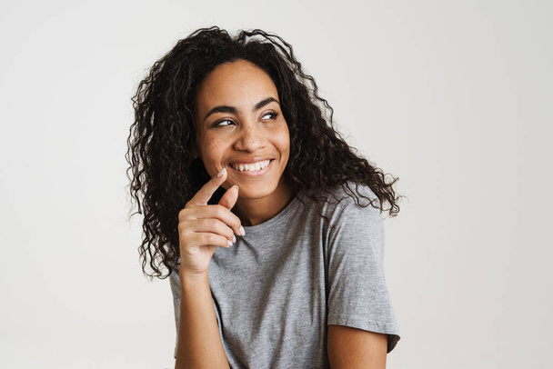Young black woman with wavy hair laughing and looking aside isolated over white background - Fotó, kép