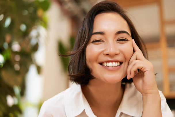 Close up retrato de engraçado jovem mulher asiática, sentado no café, conversando animada, sorrindo para a câmera. - Foto, Imagem