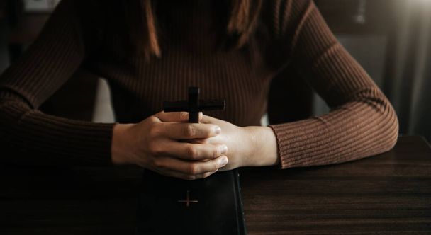 cropped view of religious woman praying, Hands at table with cross and bible book  - 写真・画像
