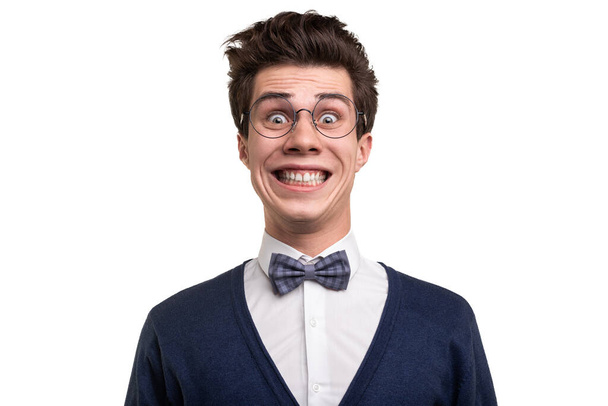 Goofy young man in smart casual clothes and glasses looking at camera with crazy smile against white background - Foto, afbeelding