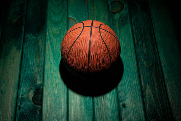 Baloncesto aislado sobre mesa de madera verde con luz desde arriba. - Foto, imagen