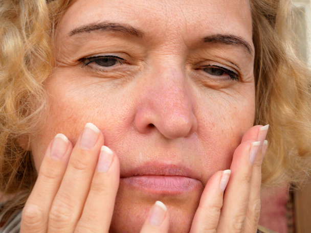 ojo de mujer de mediana edad con párpado caído haciendo masaje facial. La ptosis es una caída del párpado superior, ojo perezoso. Cosmetología y concepto facial, primeras arrugas, primer plano - Foto, imagen