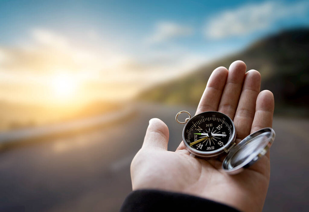 Podróżnik człowiek trzyma kompas w dłoni w górach o wschodzie słońca, punkt widzenia. - Zdjęcie, obraz