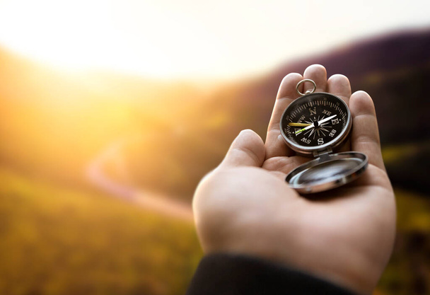 Traveler explorer man holding compass in a hand in mountains at sunrise, point of view. - Photo, Image
