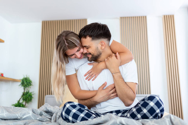 Young beautiful couple is lying in the bed at morning. Portrait of a relaxed young couple lying in bed at home. Beauty portrait. - Foto, Bild