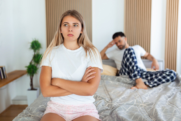 Frustrated sad girlfriend sit on bed think of relationship problems, thoughtful couple after quarrel lost in thoughts, upset lovers consider break up, offended person disappointed by boyfriend - Фото, зображення
