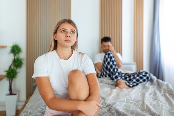 Frustrated sad girlfriend sit on bed think of relationship problems, thoughtful couple after quarrel lost in thoughts, upset lovers consider break up, offended person disappointed by boyfriend - Foto, Imagem
