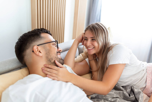 Tourné d'un jeune couple affectueux partageant un moment romantique dans la chambre à coucher à la maison - Photo, image