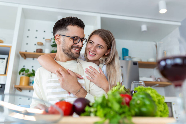 Portrait of happy young couple cooking together in the kitchen at home. romantic Attractive young woman and handsome man are enjoying spending time together while standing on light modern kitchen. - Photo, Image