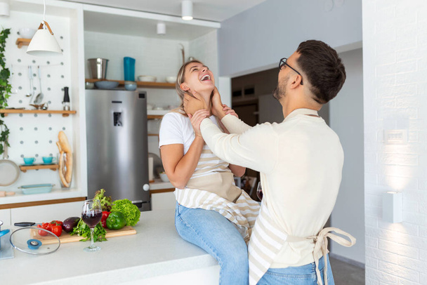 Romantic young couple cooking together in the kitchen,having a great time together. Man and woman laughing in the morning with breakfast - Photo, Image