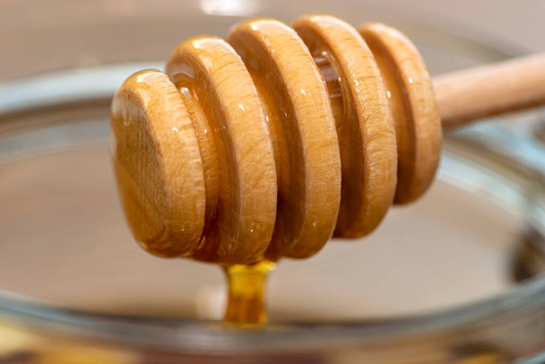 Valkosipuli hunajalla lasipurkissa keittiön pöydällä puisella hunajakepillä. - Valokuva, kuva
