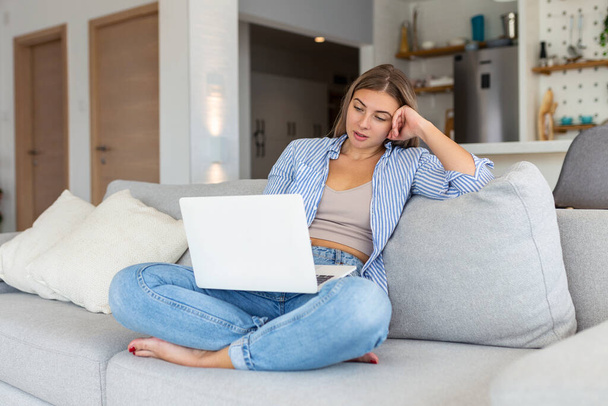 Nice beautiful lady work at the notebook sit down on the sofa at home - check on oline shops for cyber monday sales - technology woman concept for alternative office freelance - Photo, Image