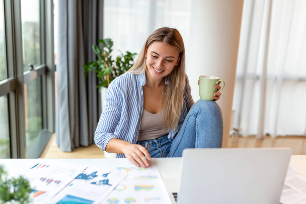 Remote job, technologie en mensen concept - gelukkig lachende jonge zakenvrouw met laptop computer en papieren werken thuis kantoor - Foto, afbeelding