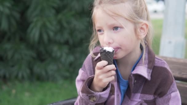 Una chica brillante de 6 años come helado en el parque. - Metraje, vídeo