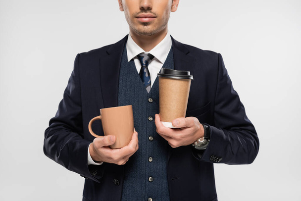cropped view of businessman holding paper cup and mug isolated on grey - Fotografie, Obrázek
