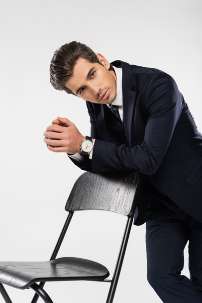 successful businessman in formal wear standing near chair isolated on grey - Fotoğraf, Görsel