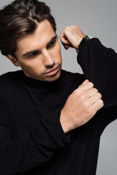 portrait of good looking man in black turtleneck looking away isolated on grey - Photo, image