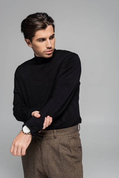 good looking man in black turtleneck looking away while posing isolated on grey - Foto, Imagem