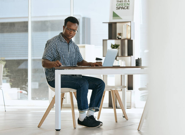 Black man, startup business and employee with laptop working in an open office for creative design, digital marketing and advertising company. Modern workplace, strategy thinking and planning at desk. - Фото, изображение