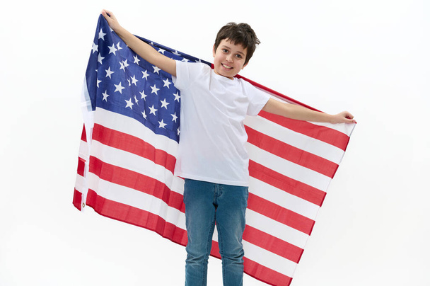 Boldog amerikai állampolgár, egy tinédzser fiú alkalmi pólóban és kék farmer farmerben, amerikai zászlóval a kezében, július 4-én ünnepli a függetlenség napját. A szabadság, a szabadság és az állampolgárság fogalma - Fotó, kép