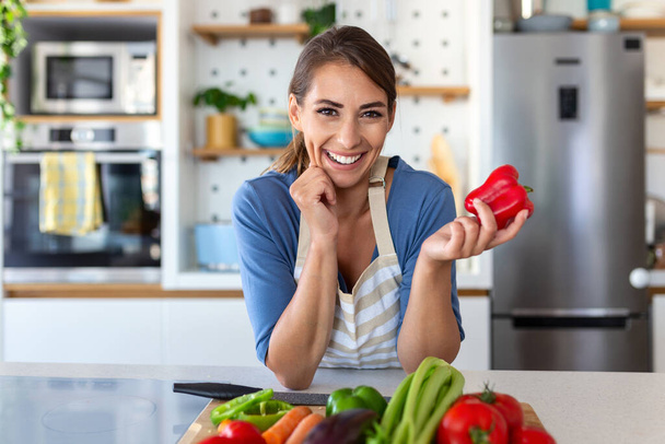 Bonito feliz jovem morena de bom humor preparando uma salada vegan fresco para uma vida saudável na cozinha de sua casa. - Foto, Imagem