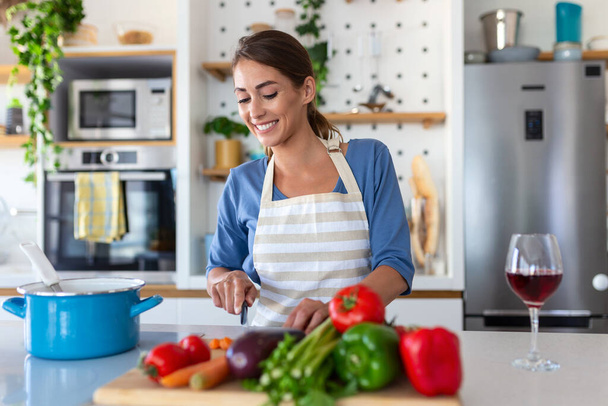 Piękna młoda kobieta stoi w nowoczesnej kuchni chop warzywa przygotować świeżą sałatkę warzywną na obiad lub obiad, młoda kobieta gotowania w domu zrobić śniadanie po zdrowej diecie, wegetariańska koncepcja - Zdjęcie, obraz