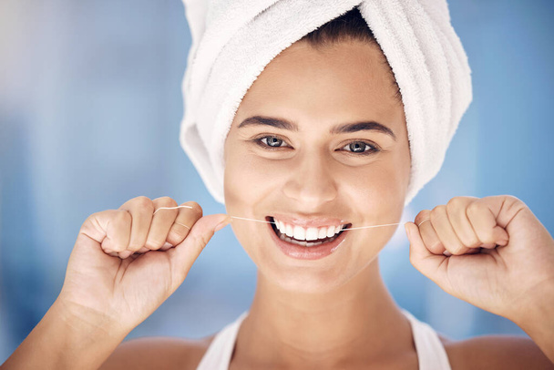 Face, dental and woman flossing teeth for oral health and hygiene. Portrait, tooth wellness and happy, healthy and young female from Canada with smile cleaning mouth for dental care in the morning. - Foto, imagen