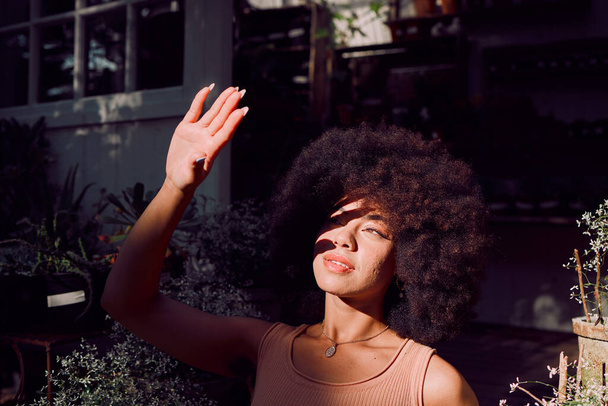 Sun, shadow and hand with a black woman covering her face from the light while standing outdoor. Beauty, afro and sunlight with an attractive young female blocking her head and skin from sunshine. - Foto, Imagem