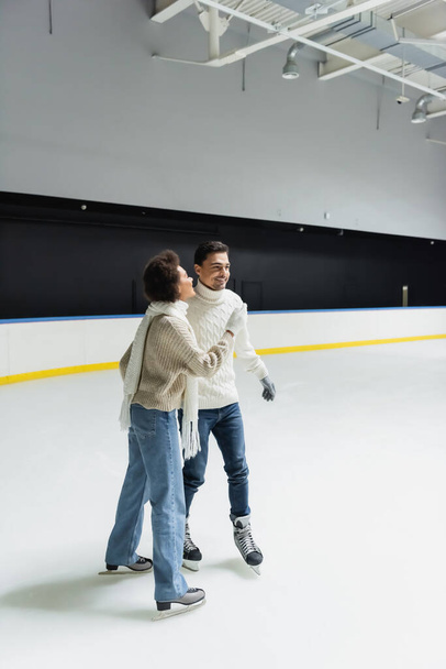 Jeune femme afro-américaine patinage sur glace tout en passant du temps avec son petit ami sur la patinoire  - Photo, image