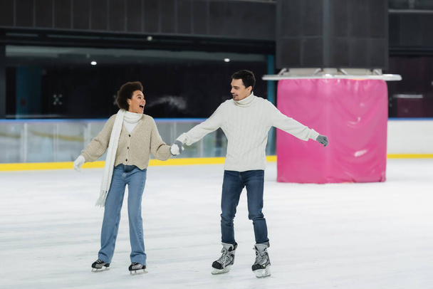 Excited african american woman ice skating with boyfriend on rink  - Foto, immagini