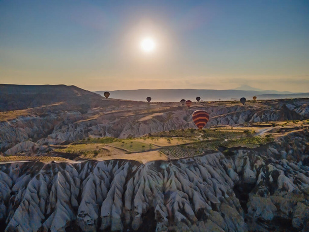 Colorful hot air balloons flying over at fairy chimneys valley in Nevsehir, Goreme, Cappadocia Turkey. Spectacular panoramic drone view of the underground city and ballooning tourism. High quality. - Valokuva, kuva