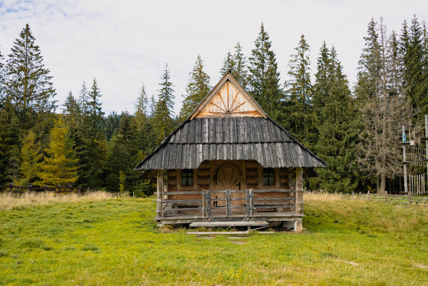Antigua casa de madera en las montañas Tatras, casa de campo con granero, prados y montañas en el fondo.  - Foto, imagen