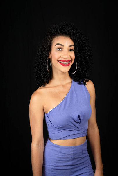 Young beautiful woman, smiling, wearing blue outfit. looking at the camera. Isolated on black background in studio - Foto, Imagen