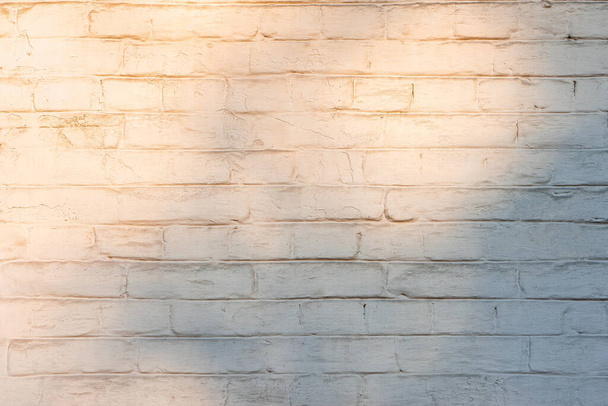 日没の光から抽象的な影を持つ白いレンガの壁の背景。建築要素、石積み、レンガ造りの花崗岩の石造りの構造。壁紙背景 - 写真・画像