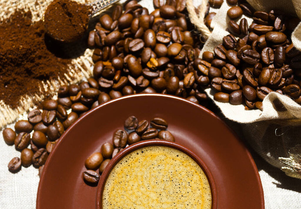 Espresso koffie op een achtergrond van koffie en gemalen bonen op jute. Arabica is de meest voorkomende vorm van koffie. - Foto, afbeelding