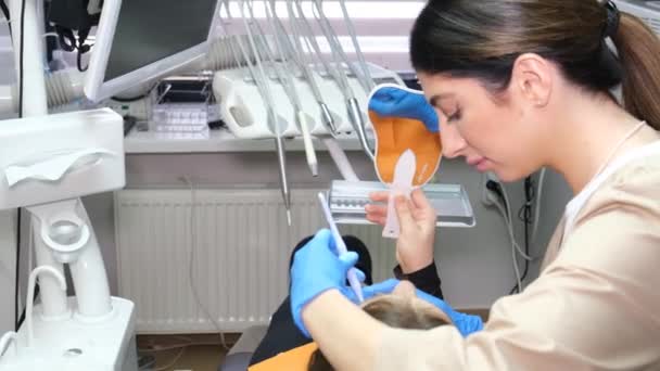 Női fogorvos a munkahelyén beteggel. Fogorvosi rendelőben, kivizsgálás.Fogászat, egészséges fogak, orvostudomány és egészségügyi koncepció - Felvétel, videó