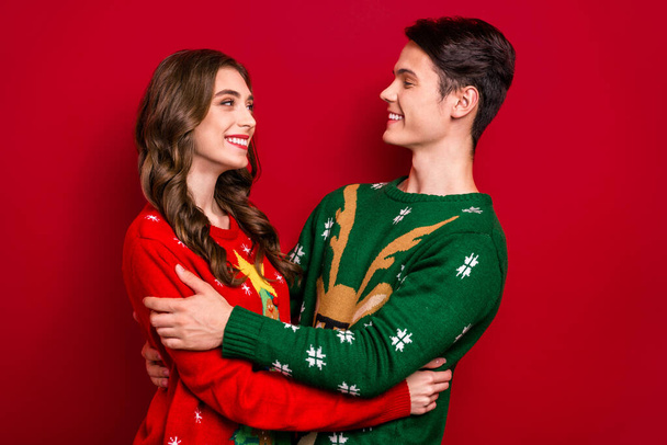 Profile portrait of two cheerful lovely partners cuddle look each other toothy smile isolated on red color background. - Foto, imagen